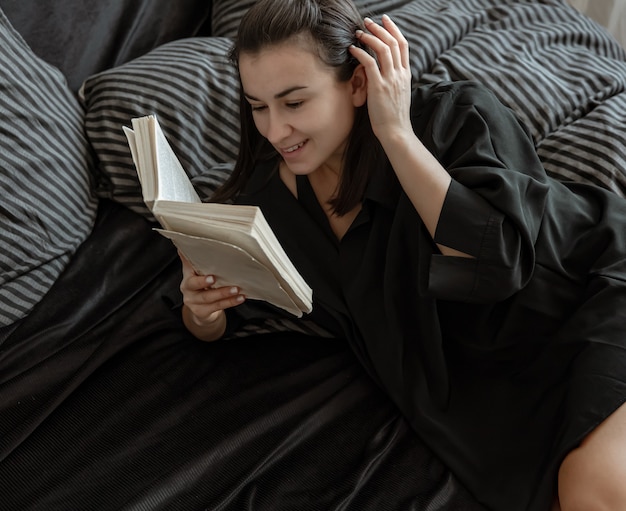 Mulher lê um livro deitada na cama como ritual noturno para desligar os pensamentos